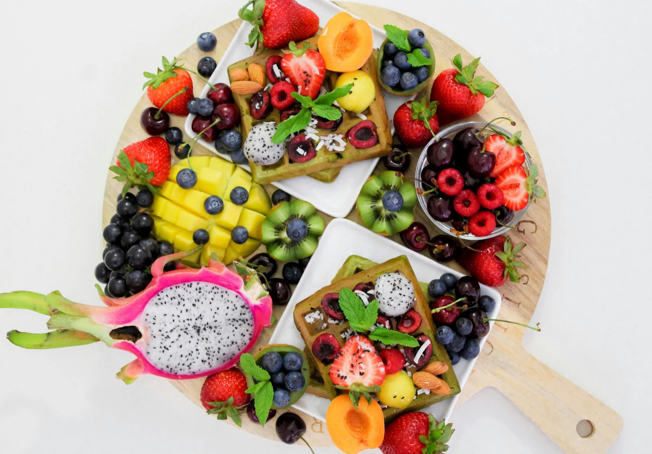 A vibrant and colorful platter of assorted fresh fruits including dragon fruit, berries, and sliced mango, perfect for healthy eating.